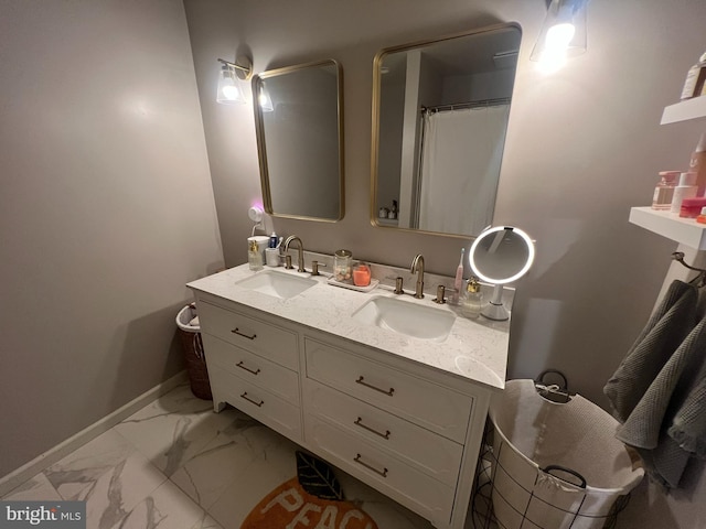bathroom with marble finish flooring, double vanity, and baseboards