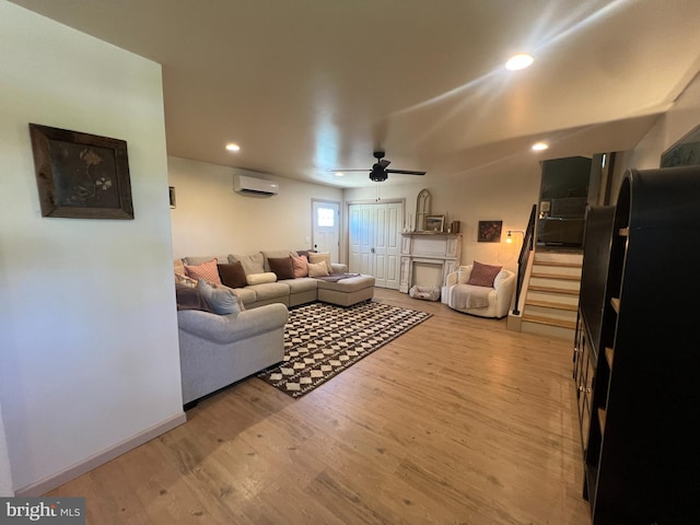 living room with a wall unit AC, light wood-style flooring, a ceiling fan, and recessed lighting