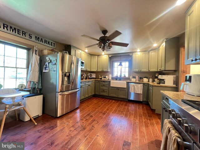 kitchen featuring stainless steel appliances, a sink, ceiling fan, and dark wood-type flooring