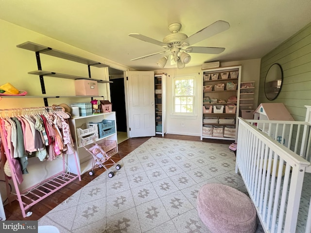 bedroom featuring wooden walls, a ceiling fan, and a wall mounted air conditioner