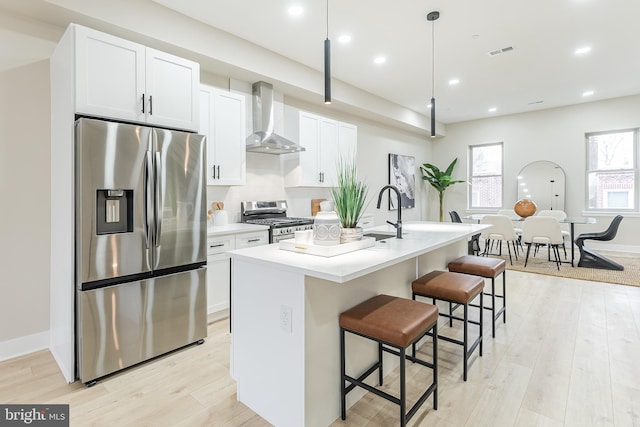 3221 Mercer St, Philadelphia, PA 19134 - kitchen with stainless steel appliances, wall chimney range hood, a center island with sink, a sink, and light wood-style floors