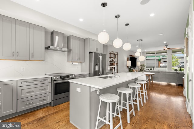 5415 9th St NW Unit 1, Washington, DC 20011 - kitchen featuring wall chimney exhaust hood, appliances with stainless steel finishes, gray cabinetry, a sink, and open floor plan