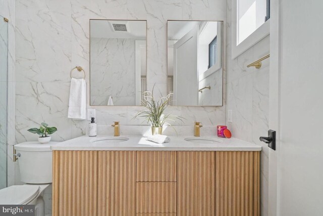 bathroom with tile walls, double vanity, backsplash, and toilet