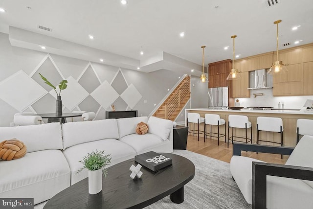 living room featuring recessed lighting, light wood finished floors, stairs, and baseboards