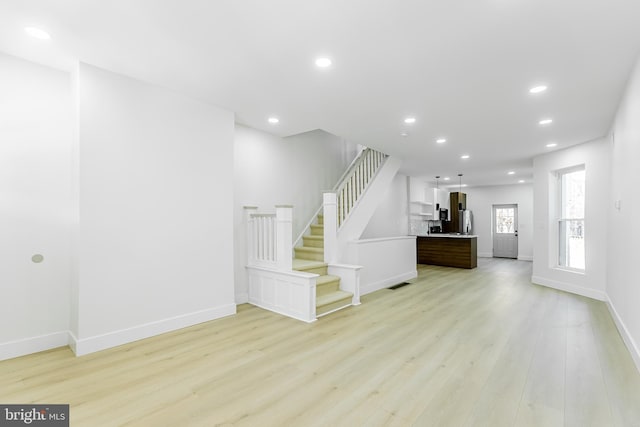 unfurnished living room featuring light wood-style flooring, stairs, recessed lighting, and baseboards