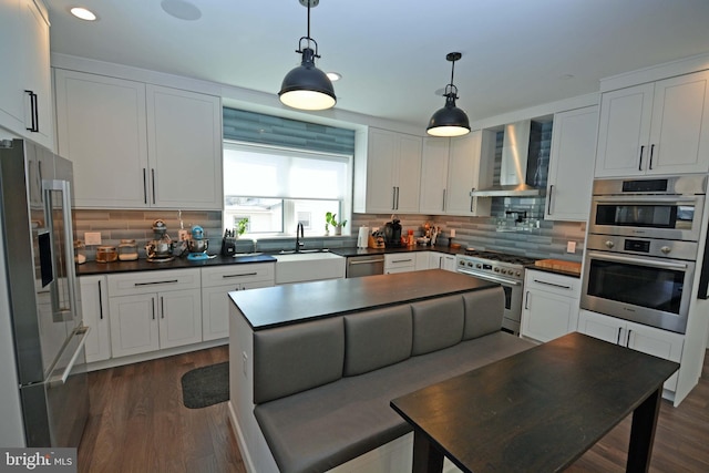 7012 Silverwood St, Philadelphia, PA 19128 - kitchen featuring stainless steel appliances, wall chimney range hood, a sink, dark countertops, and decorative backsplash