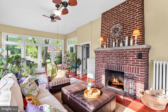 living room featuring radiator heating unit, a ceiling fan, a fireplace, and tile patterned flooring