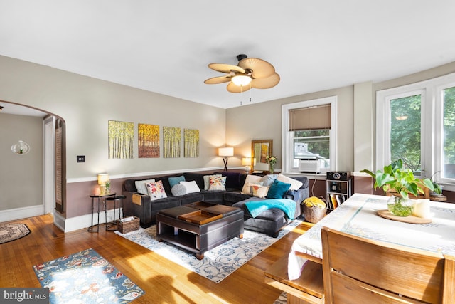 living area featuring healthy amount of natural light, wood finished floors, arched walkways, and a ceiling fan