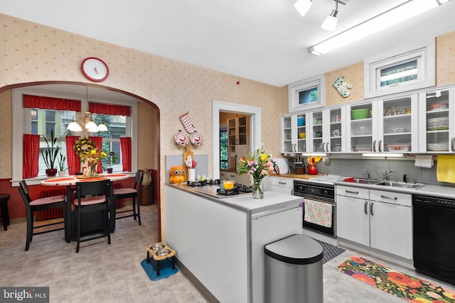 kitchen featuring wallpapered walls, black appliances, a sink, white cabinets, and light countertops