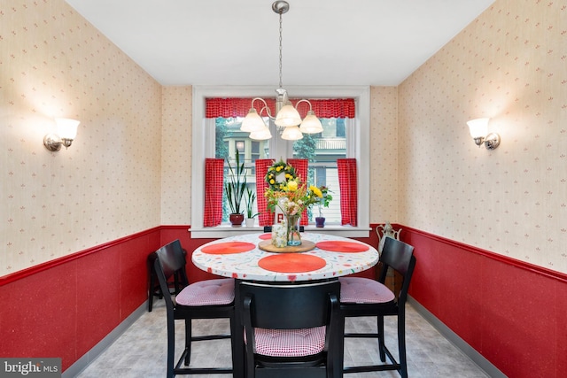 dining room featuring a chandelier, wallpapered walls, and a wainscoted wall