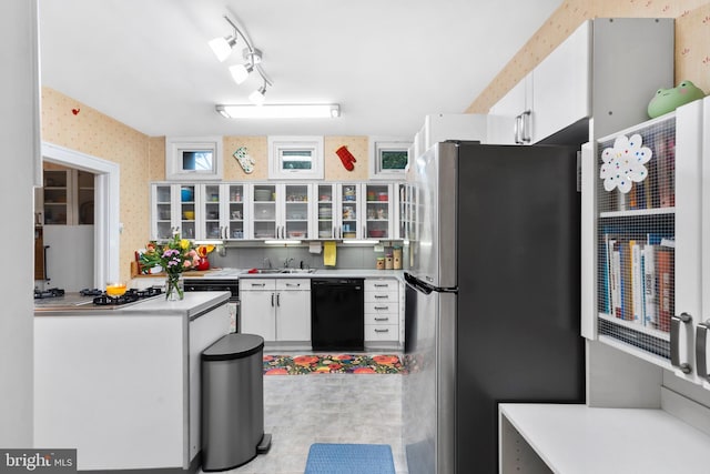 kitchen with appliances with stainless steel finishes, white cabinetry, light countertops, wallpapered walls, and glass insert cabinets