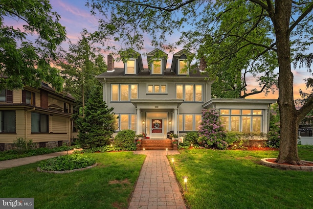 view of front of home with a lawn, a chimney, and stucco siding
