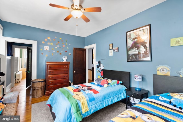 bedroom featuring wood finished floors, radiator, and ceiling fan