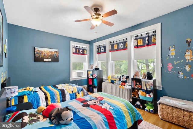 bedroom featuring radiator heating unit, wood finished floors, and ceiling fan
