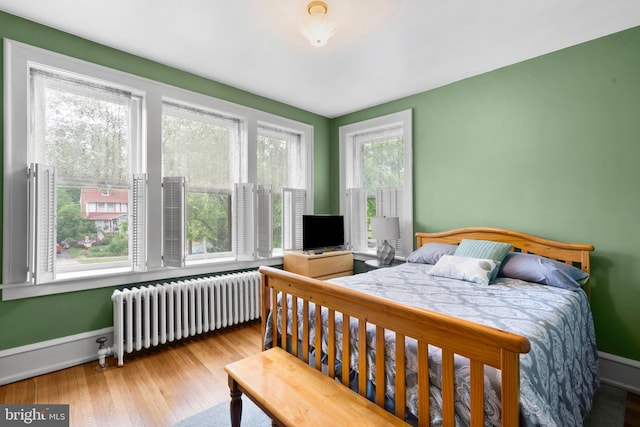 bedroom featuring radiator heating unit, wood finished floors, and baseboards