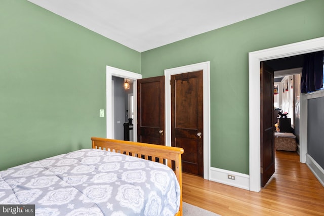 bedroom featuring light wood finished floors and baseboards