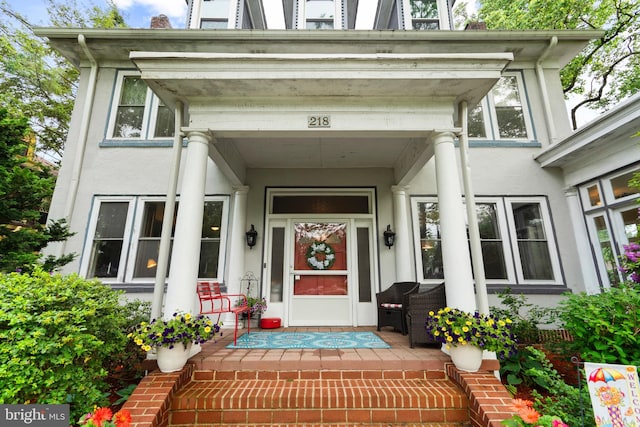 property entrance with stucco siding and covered porch
