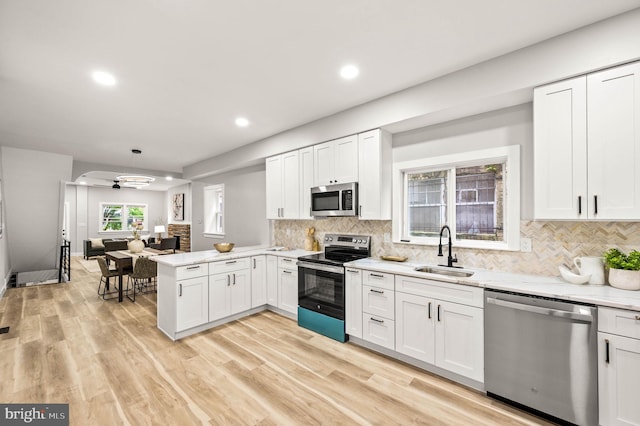 5113 W Thompson St, Philadelphia, PA 19131 - kitchen with appliances with stainless steel finishes, a sink, a peninsula, recessed lighting, and decorative backsplash