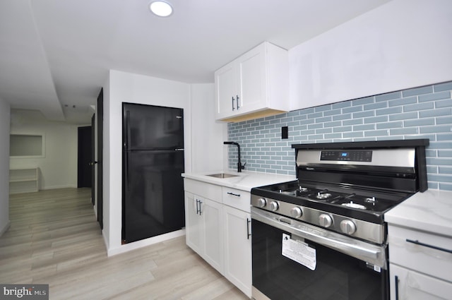 8922 Brous Ave, Philadelphia, PA 19152 - kitchen featuring stainless steel range with gas cooktop, a sink, freestanding refrigerator, decorative backsplash, and white cabinets