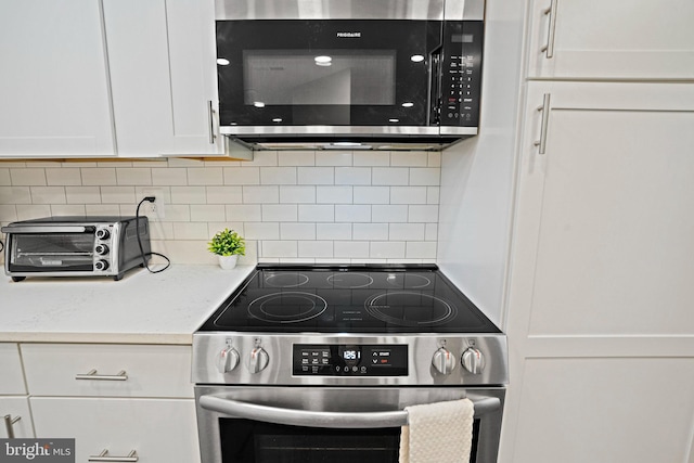 kitchen featuring stainless steel electric range, white cabinets, decorative backsplash, and light stone countertops
