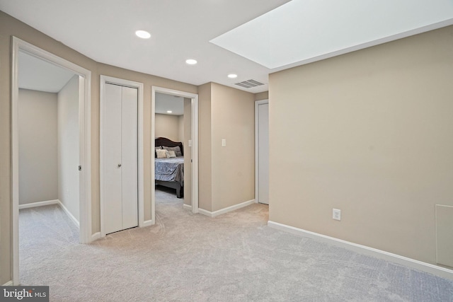 unfurnished bedroom featuring light carpet, recessed lighting, and baseboards