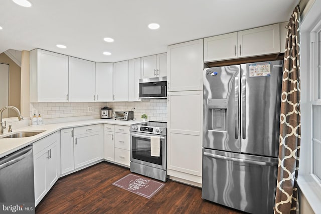 kitchen featuring appliances with stainless steel finishes, a sink, dark wood-type flooring, white cabinets, and recessed lighting