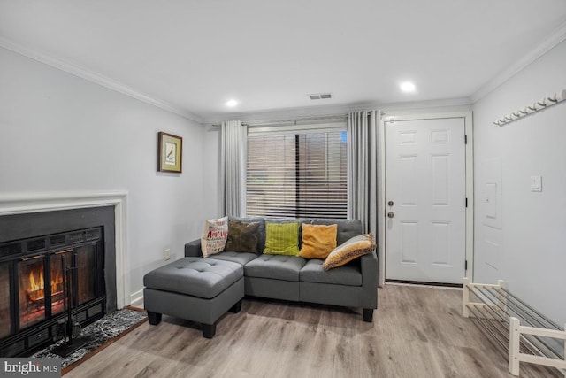 living area with crown molding, light wood-type flooring, a fireplace with flush hearth, baseboards, and recessed lighting