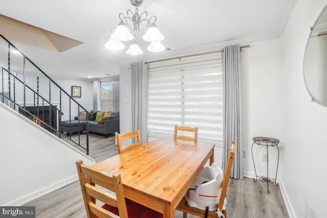 dining area featuring wood finished floors, crown molding, a chandelier, stairs, and baseboards