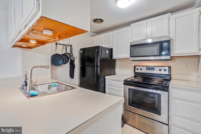 kitchen featuring stainless steel appliances, a sink, white cabinetry, light countertops, and light tile patterned floors