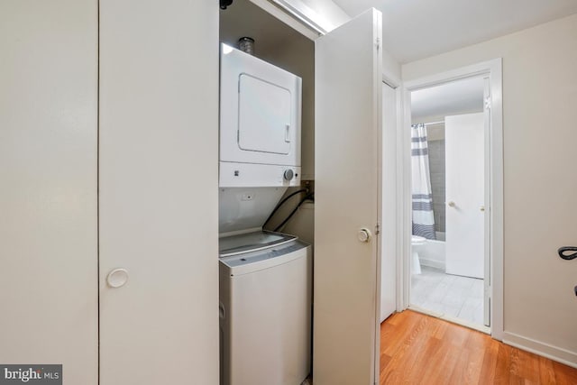 laundry area with stacked washing machine and dryer and light wood finished floors