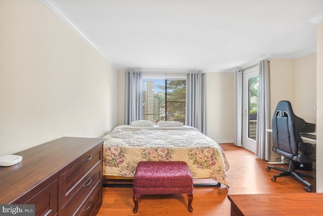 bedroom featuring crown molding, light wood finished floors, and access to exterior