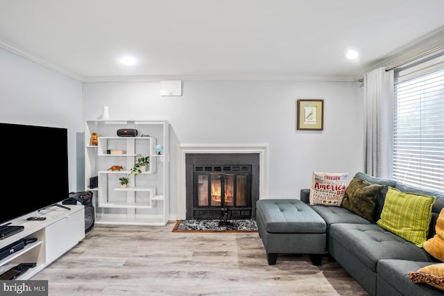 living area with ornamental molding, a fireplace with flush hearth, wood finished floors, and recessed lighting