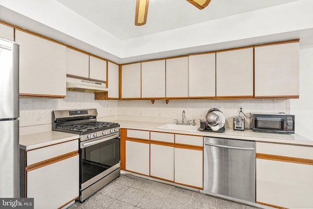 643 Saint Anthony Ln, Upper Darby, PA 19082 - kitchen featuring stainless steel appliances, under cabinet range hood, light countertops, a sink, and decorative backsplash
