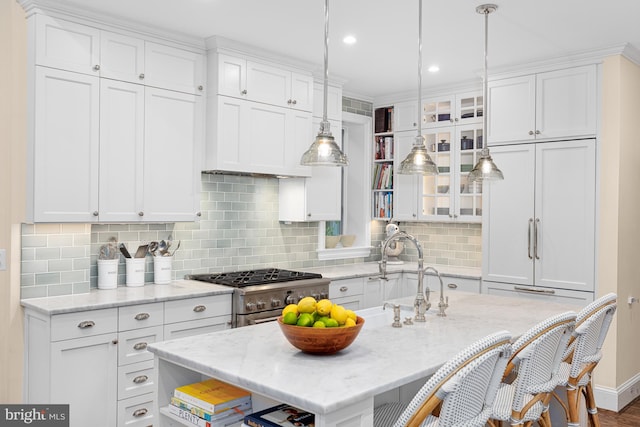 kitchen with stainless steel gas range, white cabinetry, a kitchen bar, and recessed lighting