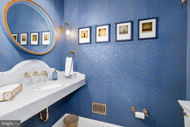 half bathroom with wallpapered walls and a sink
