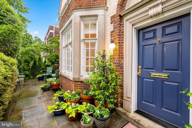 property entrance with brick siding and a patio
