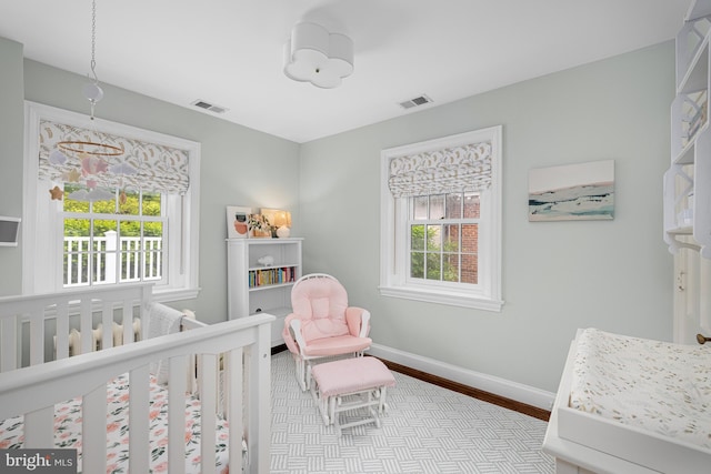 bedroom featuring multiple windows, wood finished floors, baseboards, and a crib