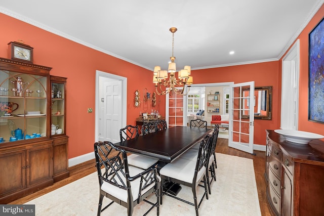 dining room featuring french doors, a chandelier, baseboards, wood finished floors, and ornamental molding