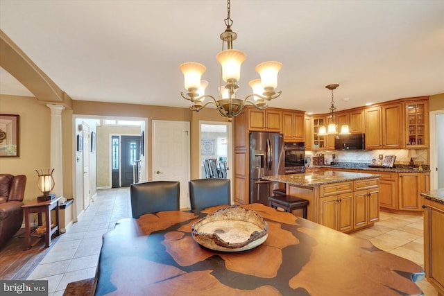 dining space with light tile patterned floors, a chandelier, and ornate columns