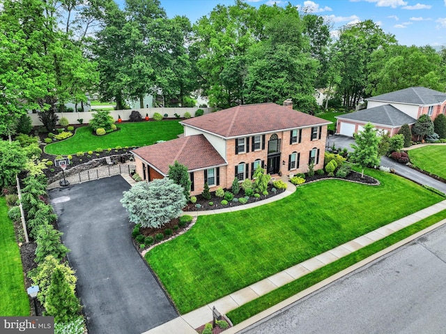 view of front of house featuring brick siding, a chimney, asphalt driveway, a gate, and a garage