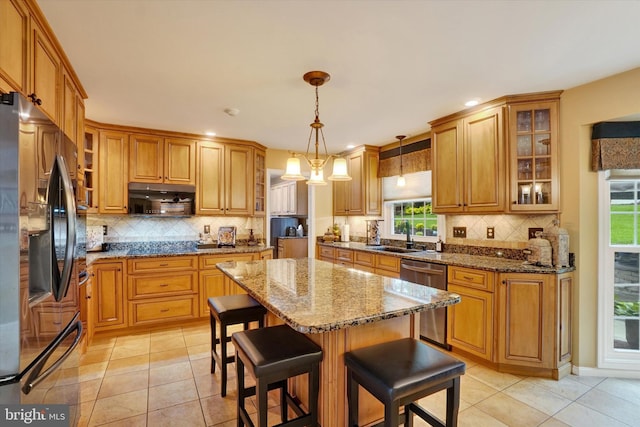 kitchen with fridge with ice dispenser, dishwasher, decorative backsplash, a kitchen island, and recessed lighting
