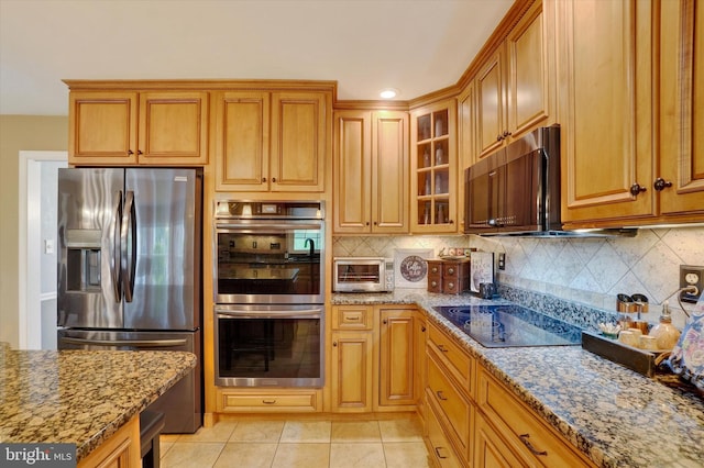 kitchen with stainless steel appliances, light stone counters, backsplash, and glass insert cabinets