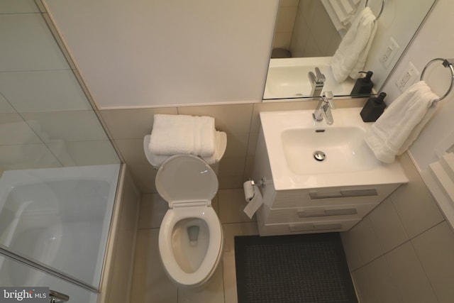 bathroom with tile walls, toilet, and vanity