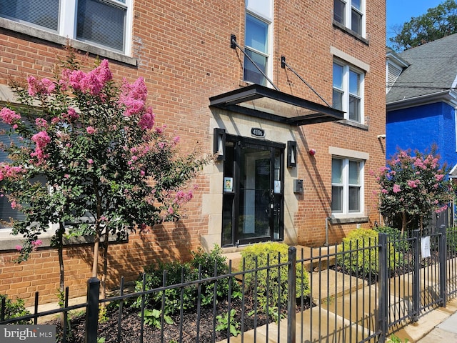 entrance to property featuring brick siding and fence