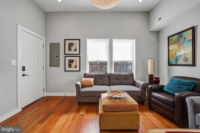 living area featuring electric panel, baseboards, light wood-style floors, and recessed lighting