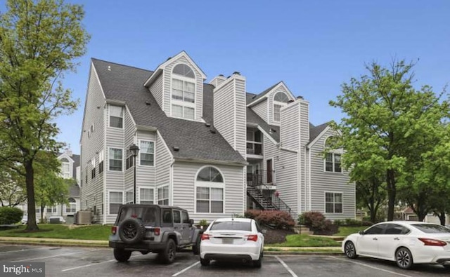 14059 Vista Dr Unit 140, Laurel, MD 20707 - view of front of house with uncovered parking, a shingled roof, stairs, a chimney, and central AC unit