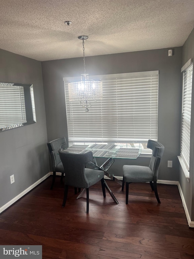 dining room with a chandelier, a textured ceiling, dark wood finished floors, and baseboards