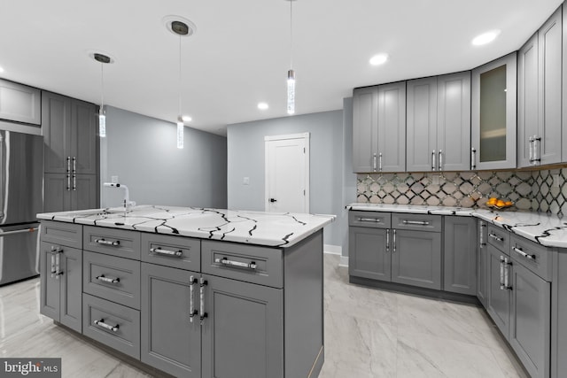 616 Webb Rd, Elkins Park, PA 19027 - kitchen featuring gray cabinetry, freestanding refrigerator, decorative backsplash, light stone counters, and a kitchen island