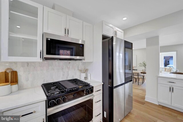8120 Eastern Ave NW, Washington, DC 20012 - kitchen featuring appliances with stainless steel finishes, white cabinets, decorative backsplash, light wood finished floors, and recessed lighting
