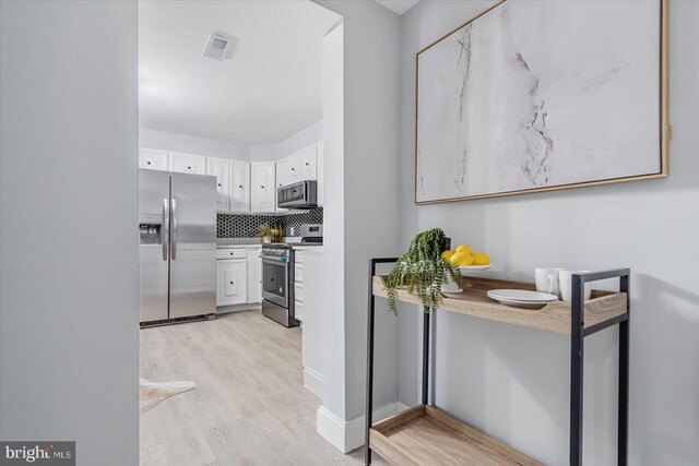 1711 Langley Rd, Baltimore, MD 21221 - kitchen with stainless steel appliances, light wood-style flooring, white cabinets, and tasteful backsplash
